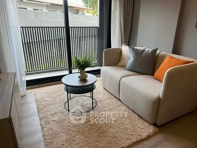Cozy living room with modern sofa and stylish decor, featuring large windows and natural light.