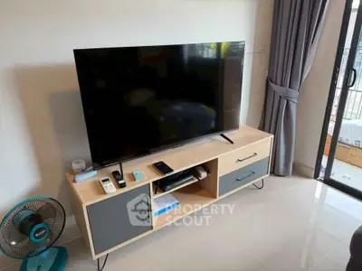 Modern living room with sleek TV stand and large flat-screen TV, complemented by elegant curtains and natural light.