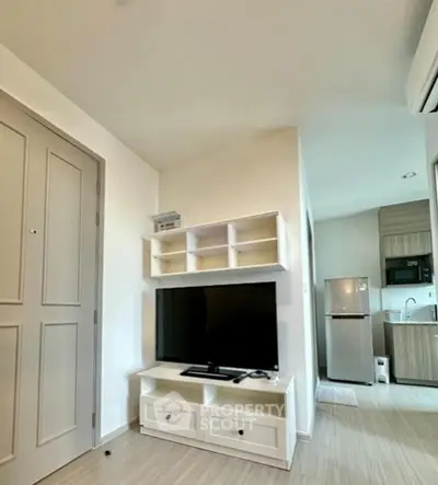 Modern apartment interior with TV unit and kitchen area, showcasing sleek design and efficient use of space.