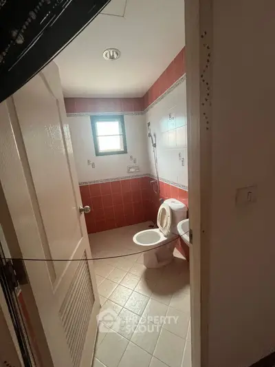 Cozy bathroom with red and white tiles, featuring a window and modern fixtures.