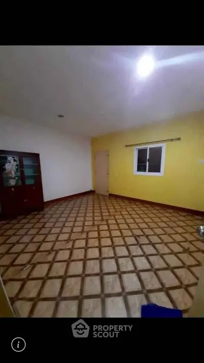 Spacious room with vibrant yellow accent wall and patterned tile flooring, ideal for versatile living space.