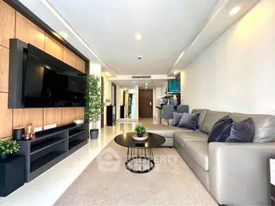 Spacious modern living room with sleek design and large TV, perfect for relaxation and entertainment.