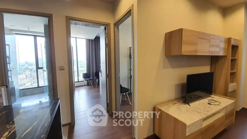 Modern apartment interior with stylish living room and city view, featuring sleek wooden furniture and elegant decor.