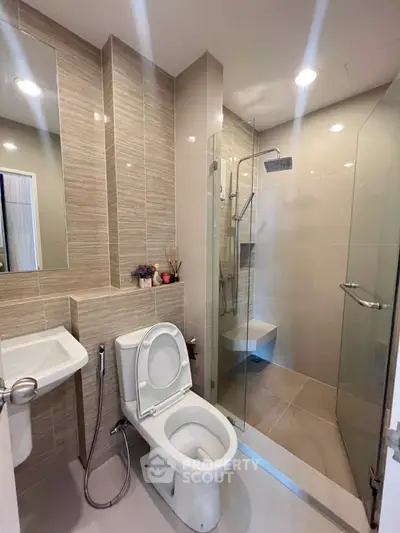 Modern bathroom with glass shower and sleek fixtures in contemporary apartment.