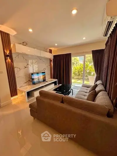 Luxurious living room with modern decor and garden view, featuring a plush sofa and sleek entertainment unit.