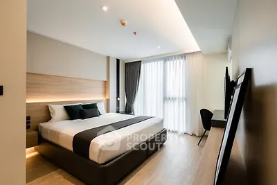 Modern bedroom with large window and stylish decor in a luxury apartment.