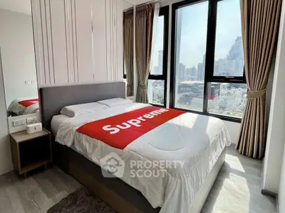 Modern bedroom with city view and stylish decor in high-rise apartment.
