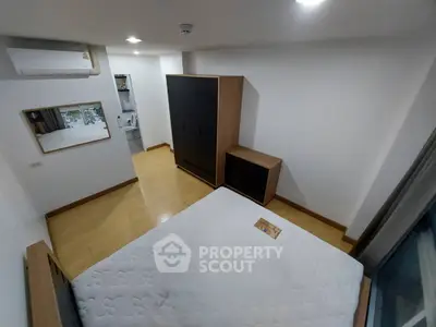 Modern bedroom with wooden flooring, sleek wardrobe, and air conditioning unit.