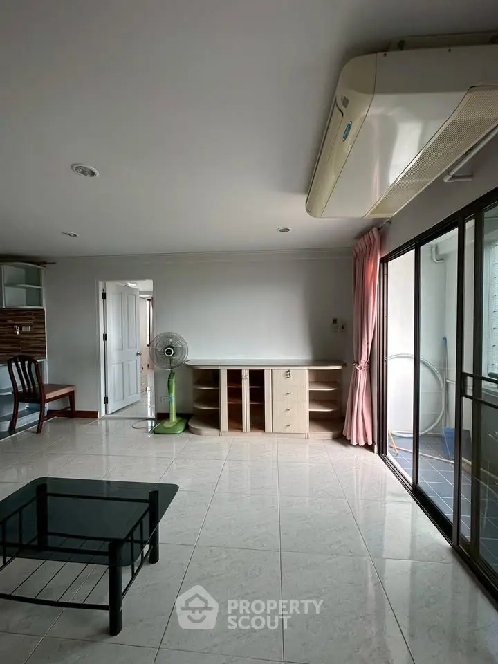 Spacious living room with modern air conditioning and sliding glass doors leading to a balcony.