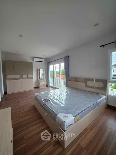Spacious bedroom with modern design and large windows offering natural light and a serene view.