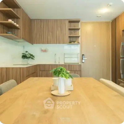 Modern kitchen with wooden cabinets and dining table, featuring sleek design and natural light.