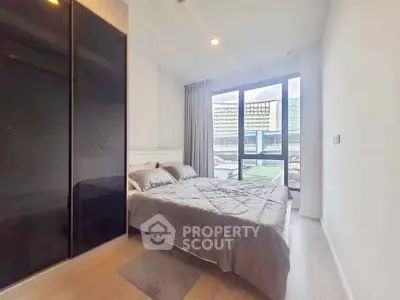 Modern bedroom with large window and city view, featuring sleek black wardrobe and cozy bedding.