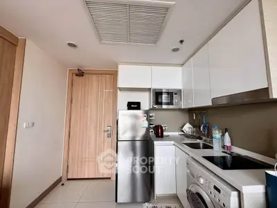 Modern compact kitchen with stainless steel appliances and washing machine