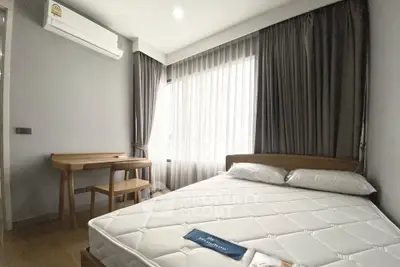 Modern bedroom with natural light, featuring a comfortable bed and a wooden desk, ideal for relaxation and work.