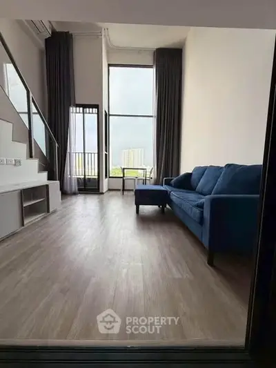 Spacious modern living room with high ceilings and large windows offering a stunning city view.