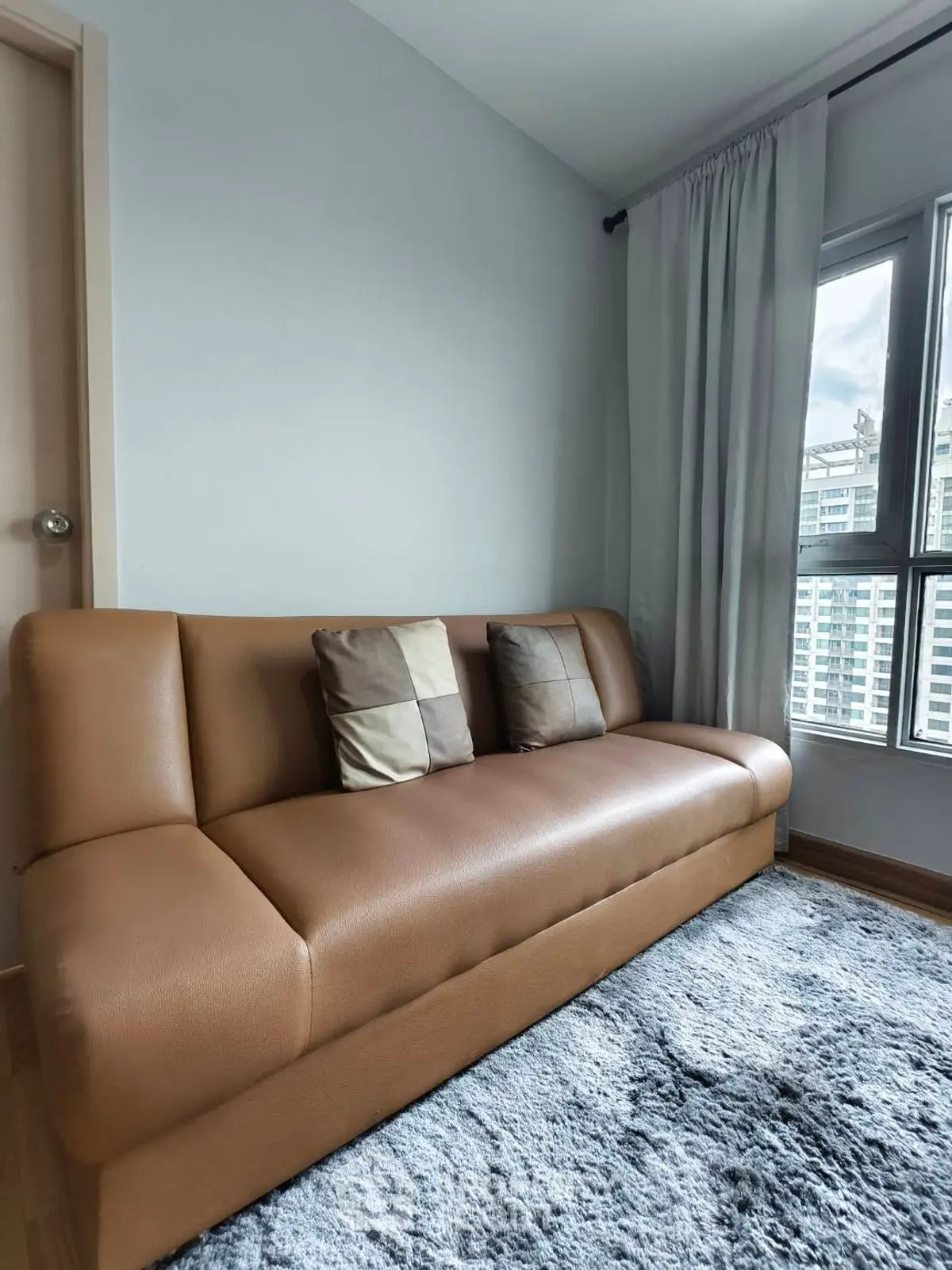 Cozy living room with modern brown sofa and large window view.