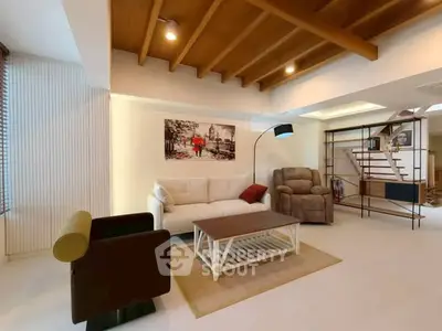 Spacious living room with modern furniture and wooden ceiling beams, ideal for family gatherings.