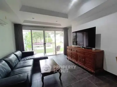 Spacious living room with modern decor and garden view, featuring a large TV and comfortable seating.