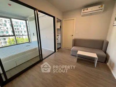 Modern apartment interior with bedroom and living area, featuring large windows and air conditioning.
