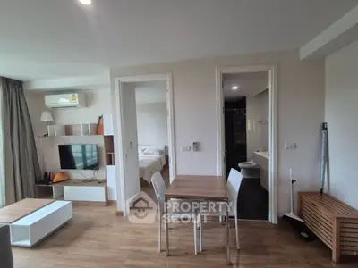 Modern open-plan living area with dining table, bedroom, and bathroom access.