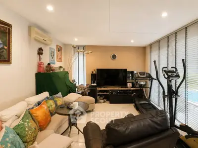 Spacious living room with modern decor and exercise equipment, featuring cozy seating and large windows.