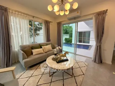 Elegant living room with pool view, modern decor, and natural light.