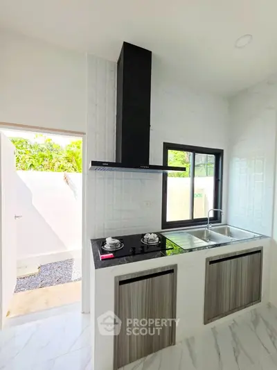 Modern kitchen with sleek gas stove and dual sink, featuring a bright and airy design with natural light.