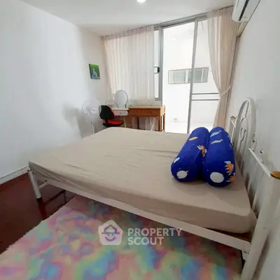 Cozy bedroom with balcony access and colorful rug, perfect for relaxation.