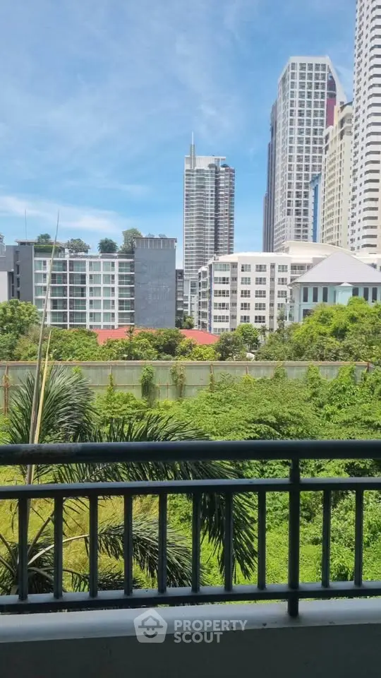 Stunning cityscape view from a balcony overlooking lush greenery and modern skyscrapers.