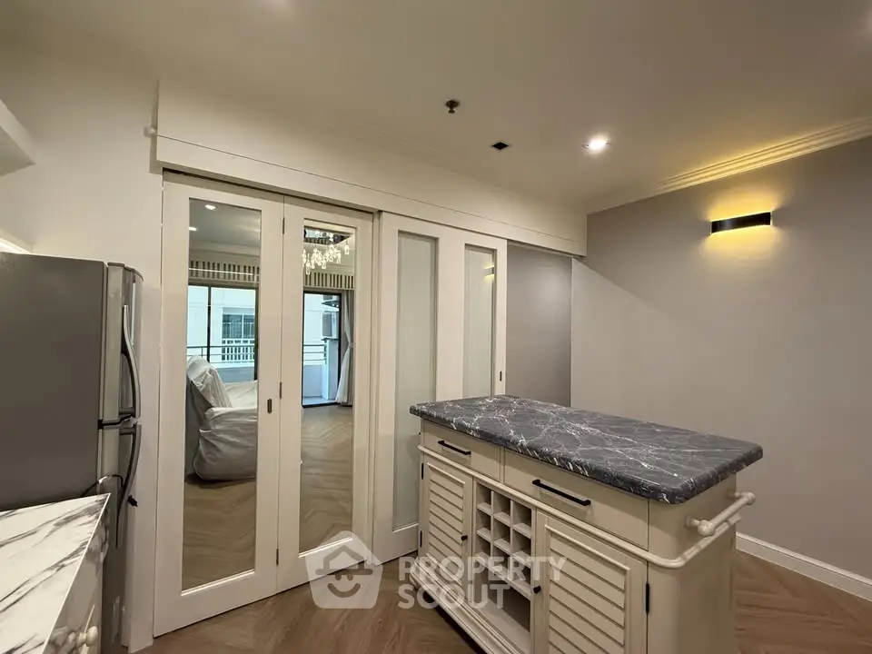 Modern kitchen with marble island and sliding glass doors leading to a bright living area.