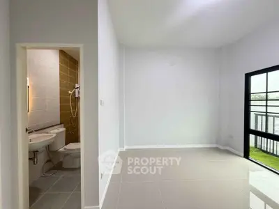Modern apartment with sleek bathroom and bright living area, featuring large windows and glossy tile flooring.