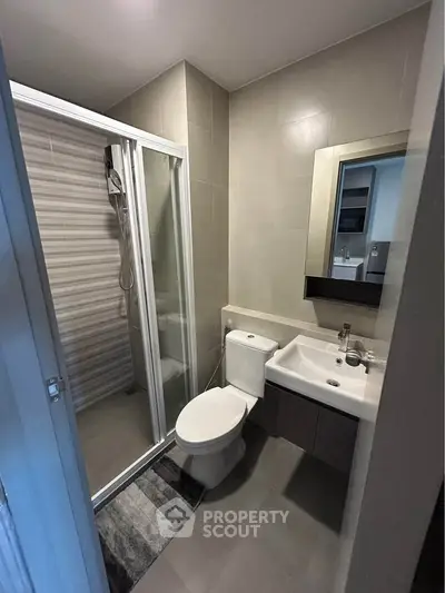 Modern bathroom with shower, toilet, and sink in sleek design.