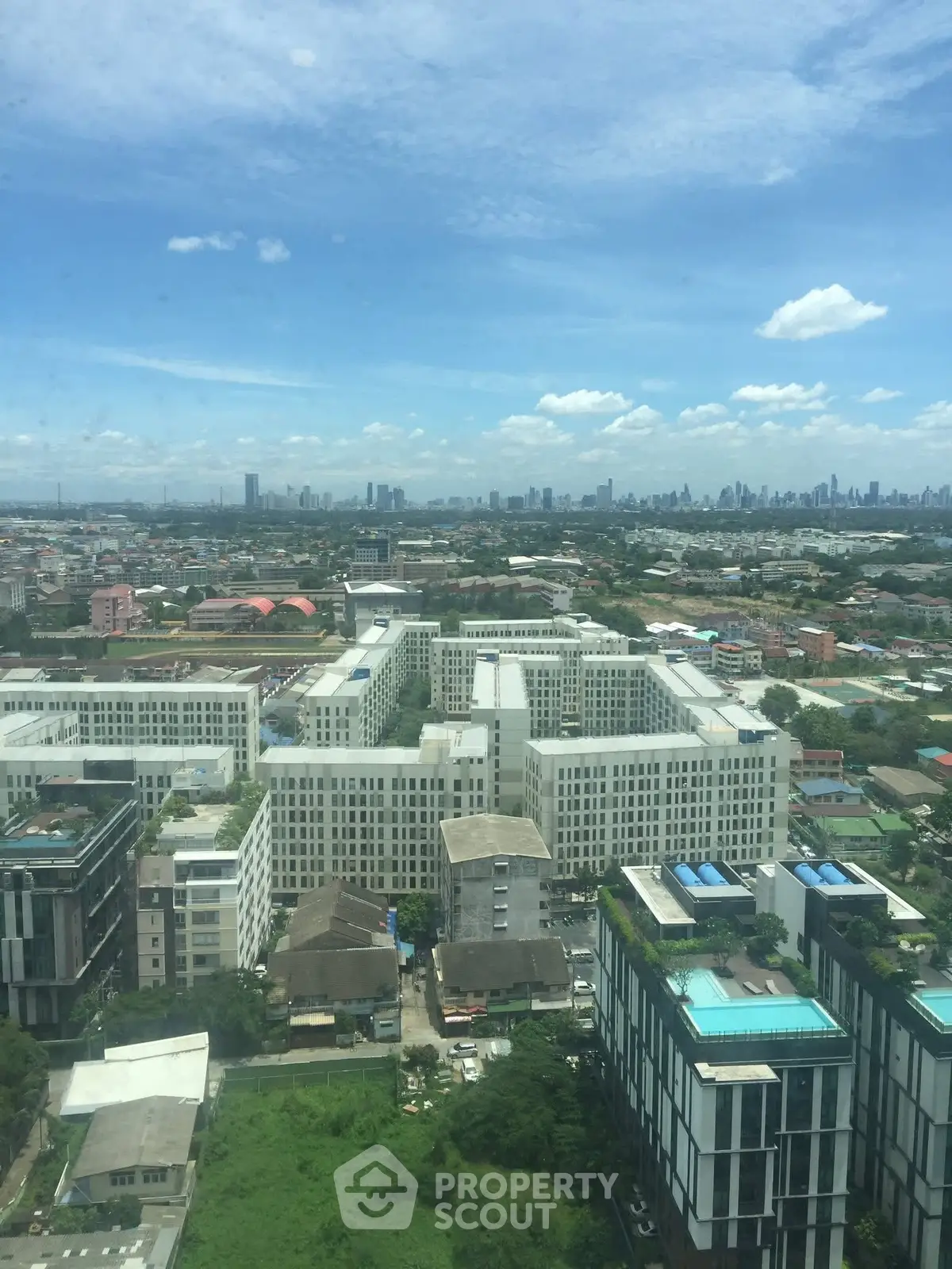 Stunning cityscape view from high-rise building with lush greenery and skyline in the background.
