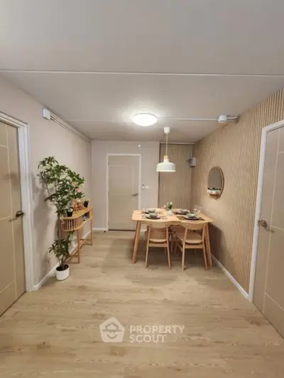 Modern dining area with wooden table, chairs, and stylish decor in a cozy apartment.