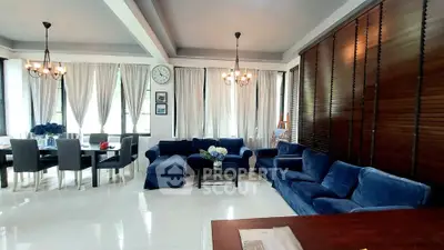 Spacious living room with elegant blue sofas and dining area, featuring large windows and stylish decor.