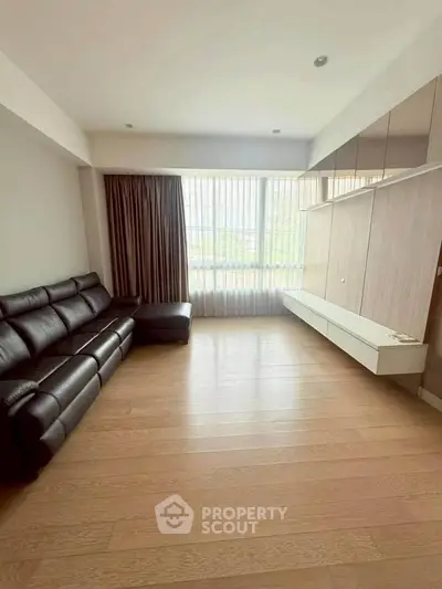 Spacious living room with modern leather sofa and large window for natural light.