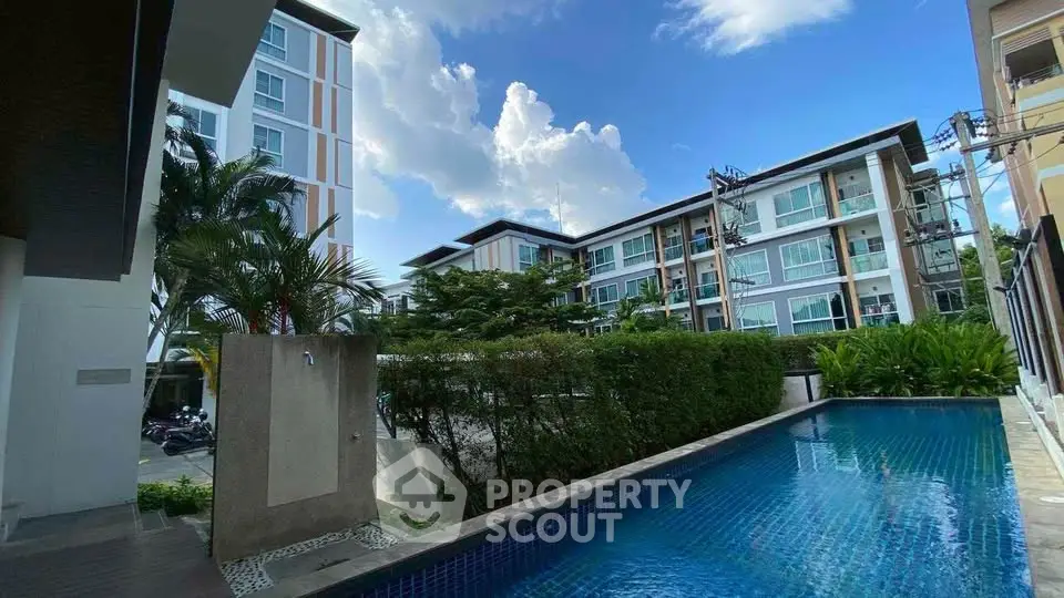 Modern apartment complex with a refreshing outdoor pool and lush greenery, perfect for relaxation and leisure.