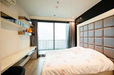 Modern bedroom with large window and stylish decor in high-rise apartment.