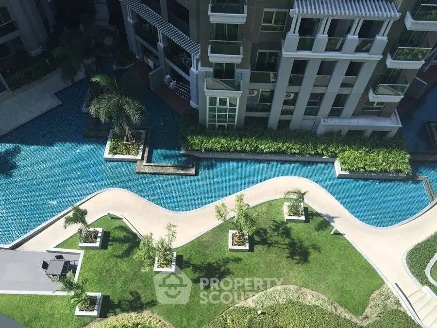Luxurious residential building with stunning pool and landscaped garden view from above.