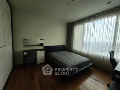 Spacious bedroom with large window and modern furnishings, offering a serene and comfortable living space.