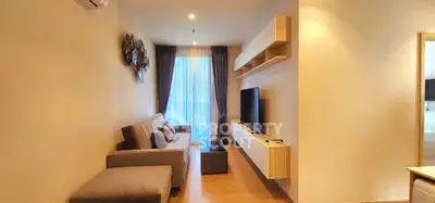Modern living room with stylish decor and natural light, featuring a comfortable sofa and wall-mounted TV.