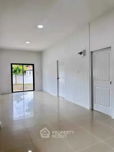 Spacious modern living room with glossy tile flooring and large window view.