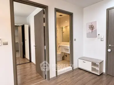 Modern apartment interior with bathroom and hallway, featuring sleek wooden doors and flooring.