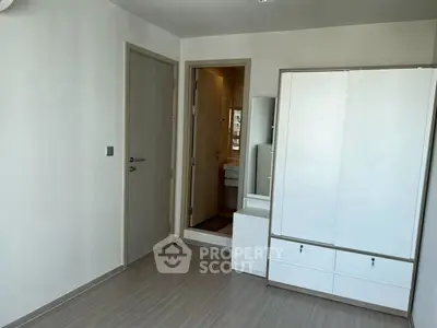 Modern bedroom with sleek wardrobe and en-suite bathroom in minimalist design.