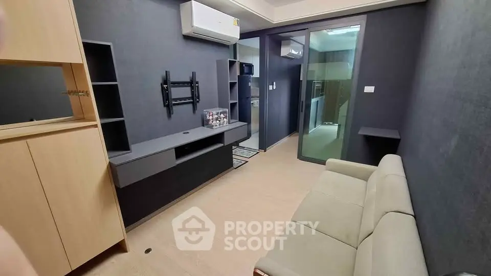 Modern living room with sleek design and air conditioning, featuring a cozy sofa and built-in shelving.