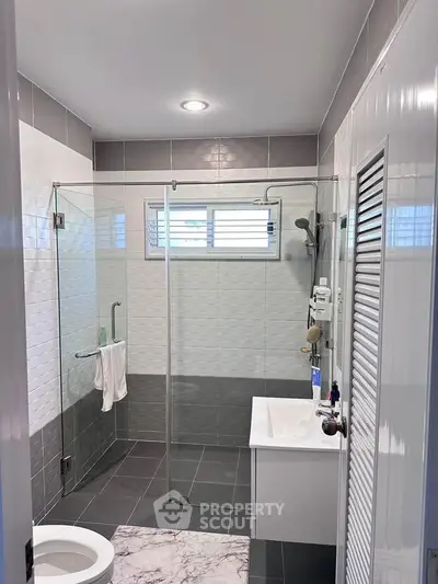 Modern bathroom with glass shower, sleek tiles, and contemporary fixtures.