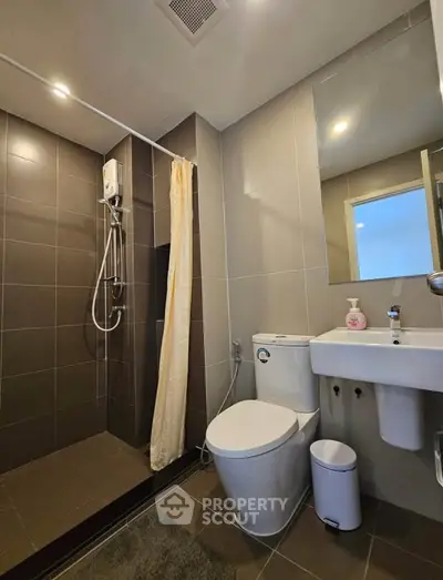 Modern bathroom with sleek design, featuring a shower area, toilet, and sink in a contemporary apartment.