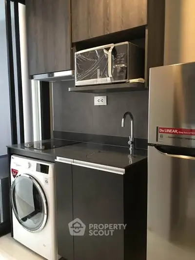 Modern compact kitchen with washer, microwave, and sleek cabinetry