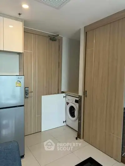 Modern apartment kitchen with integrated washing machine and sleek fridge.