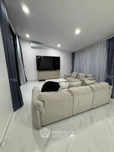 Spacious modern living room with plush seating and large TV, perfect for relaxation and entertainment.